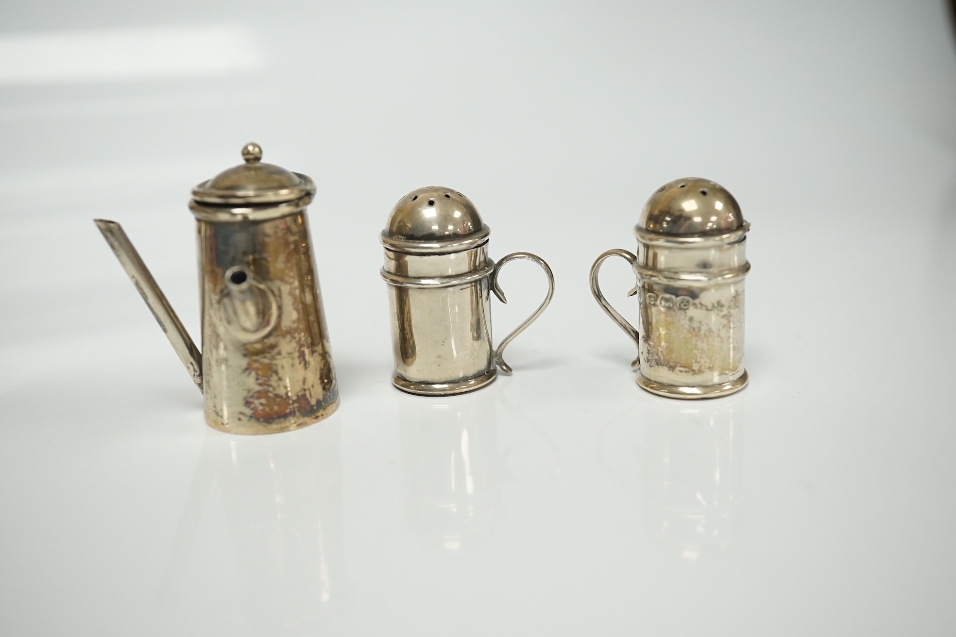 A collection of miniature silver including a three piece tea set and two handled tray by Saunders & Shepherd, Birmingham, 1904, tray 9.8cm, together with pepperettes including saucepan, candlesticks, hand mirror, etc. Co